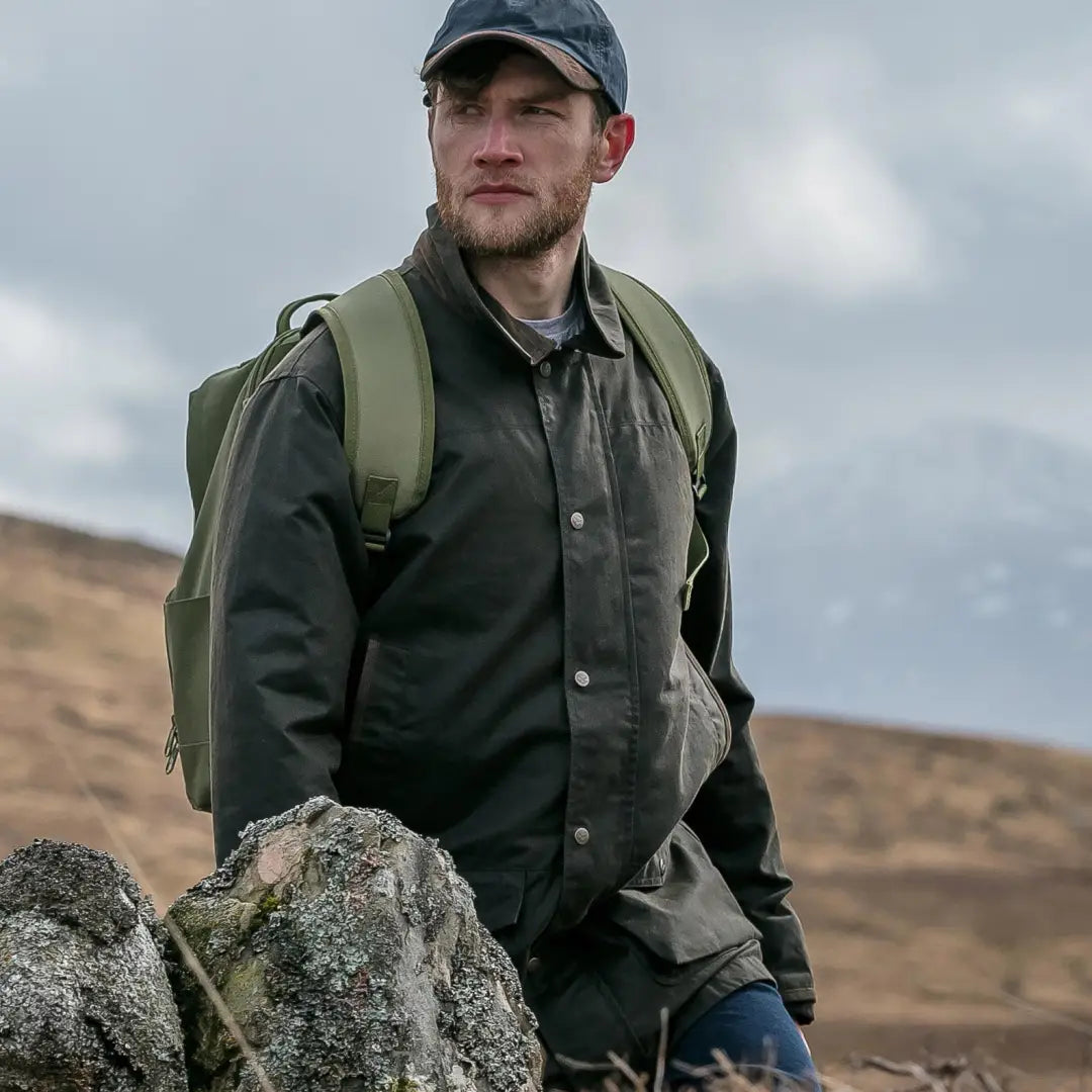 Man in Hoggs of Fife Caledonia Men’s Wax Jacket exploring rugged landscape with water resistant qualities