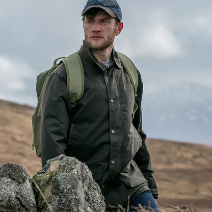 Man in Hoggs of Fife Caledonia Men’s Wax Jacket exploring rugged landscape with water resistant qualities