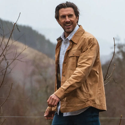 Smiling man in a tan jacket showcasing the Fife Huntly Waxed Canvas Utility Overshirt