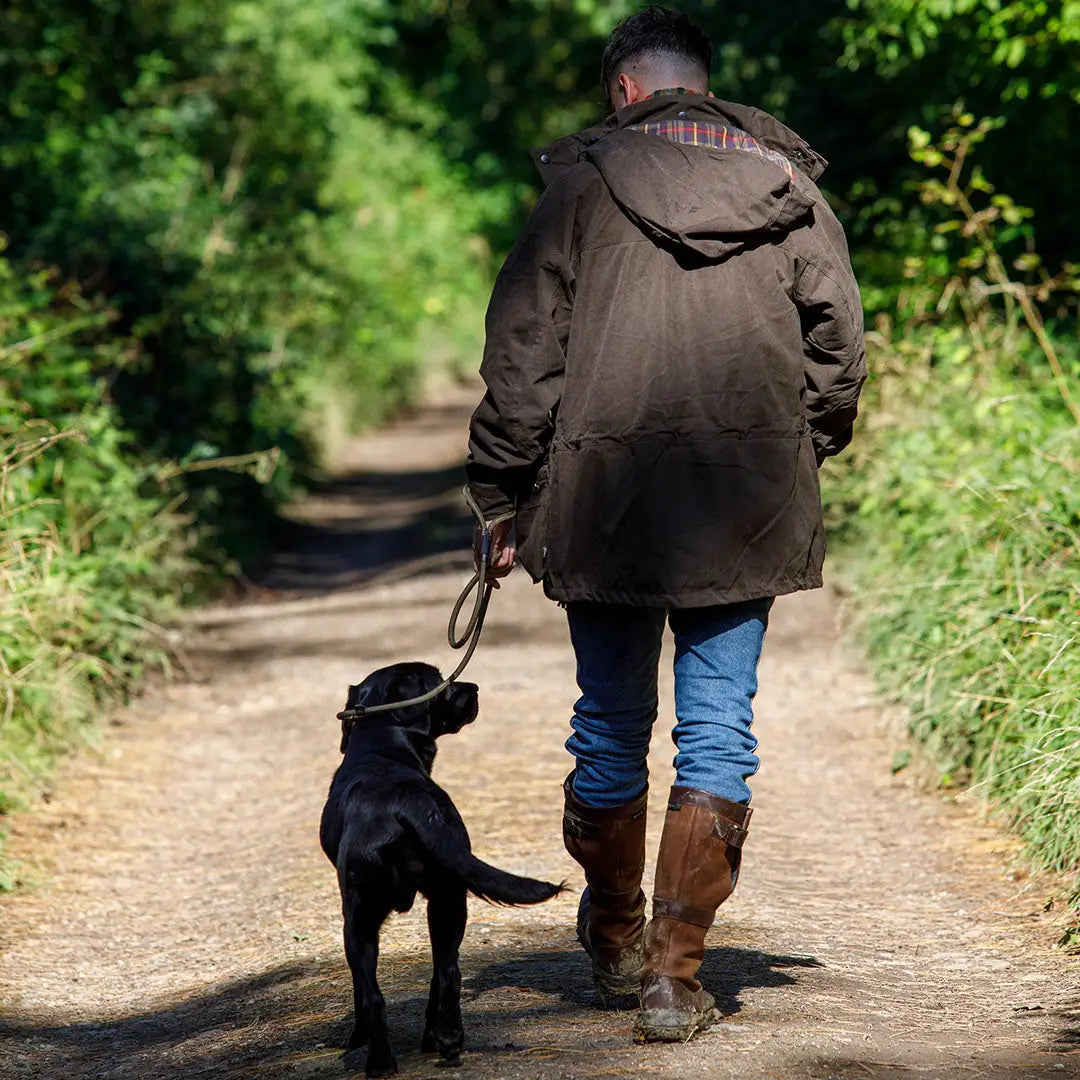 Person walking a dog while wearing a Jack Pyke Ashcombe Jacket in nature