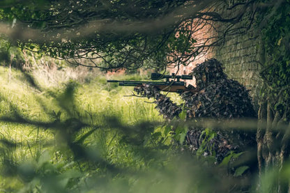Camouflaged sniper using Jack Pyke LLCS 3D Concealment Suit with rifle ready