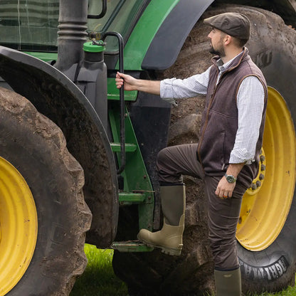 Man climbing onto a tractor wearing Jack Pyke Melange Fleece Gilet Brown