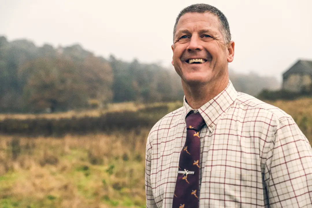 Smiling man in a patterned shirt and tie wearing a Jack Pyke Countryman shirt