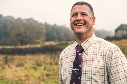 Smiling man in a patterned shirt and tie wearing a Jack Pyke Countryman shirt