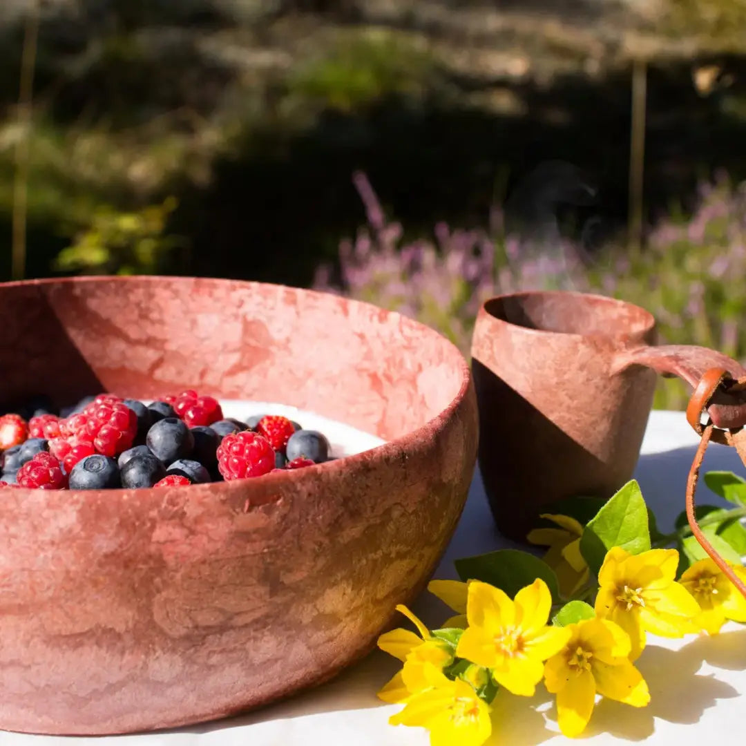 Rustic Kupilka Bowl with fresh berries and wooden mug, perfect for outdoors and hunting