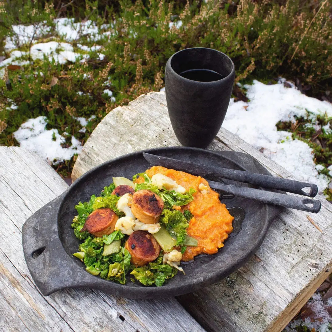 Rustic meal with sausage and greens in a Kupilka Cup, perfect for country clothing lovers