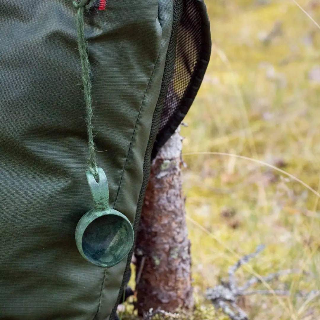 Green backpack with Kupilka Mini Cup hanging from it, perfect for outdoor adventures