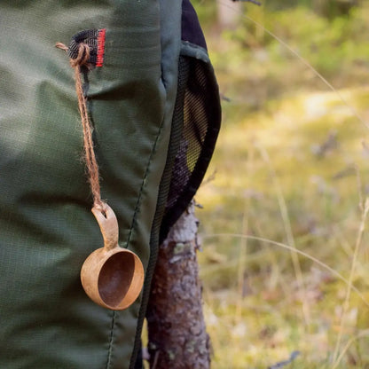 Green backpack next to a Kupilka Mini Cup made of natural materials