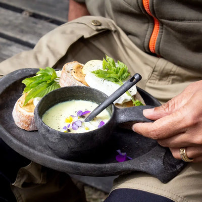 Rustic black Kupilka Plate with soup and sandwiches on a cozy country table