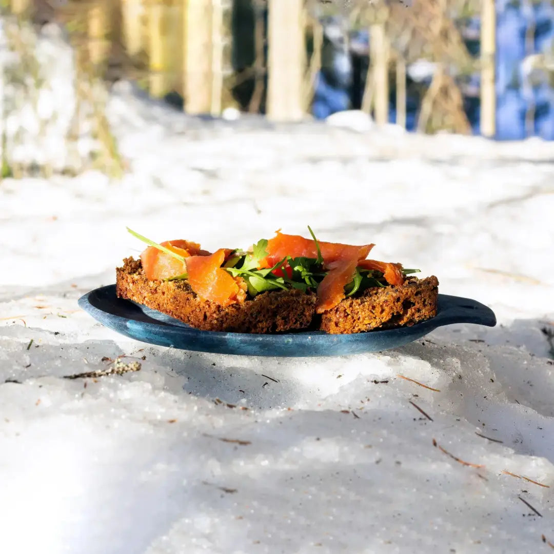 Smoked salmon on dark bread served on a Kupilka Small Plate for outdoor adventures