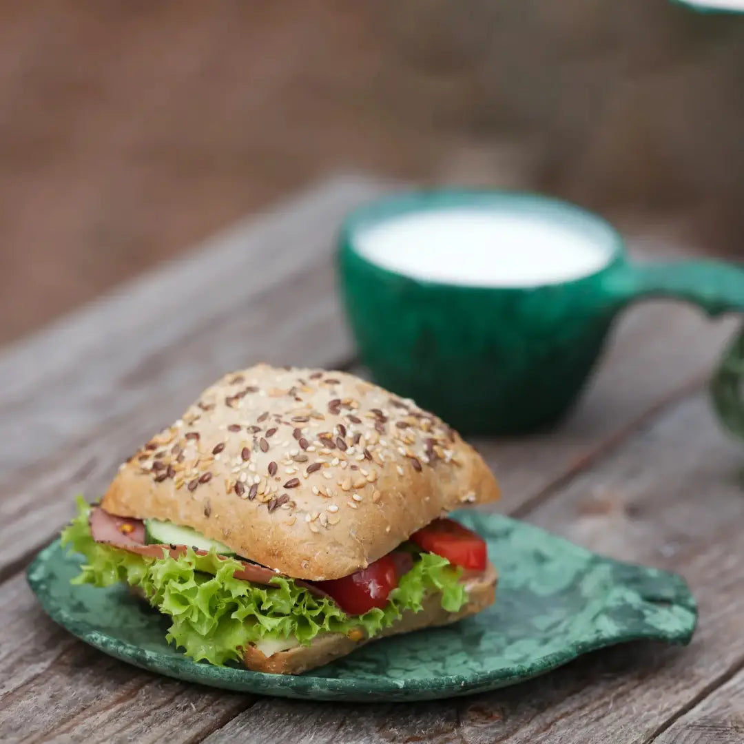 Seeded bun sandwich on Kupilka Small Plate, perfect for country clothing adventures outdoors