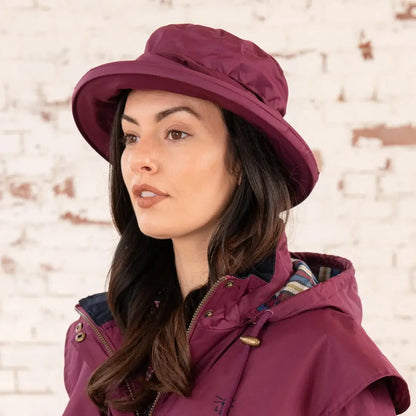 Burgundy wide-brimmed hat on a woman, perfect for the Lighthouse Canterbury Waterproof Ladies Hat
