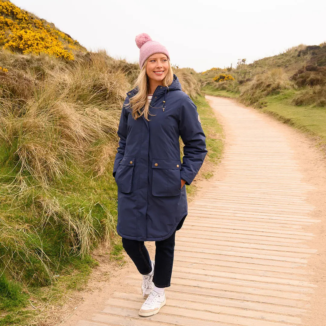 Woman in Lighthouse Imogen Ladies Coat with pink bobble hat and white trainers