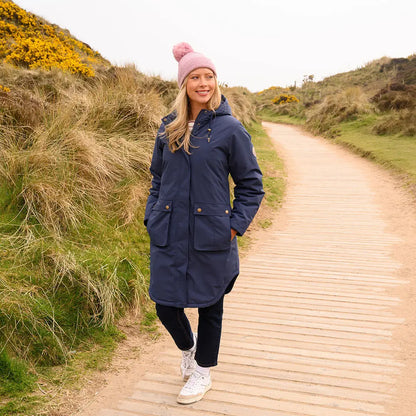Woman in Lighthouse Imogen Ladies Coat with pink bobble hat and white trainers