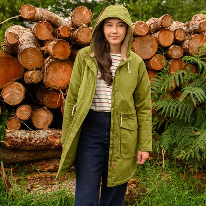 Woman wearing Lighthouse Isobel Coat in olive green parka with striped shirt and dark jeans