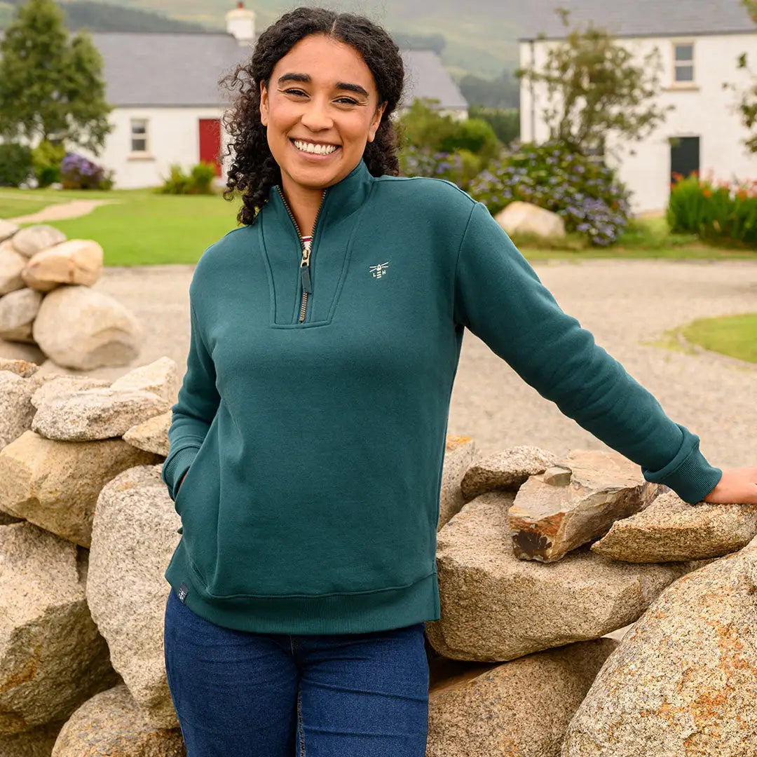 Woman in teal Lighthouse Ladies Coral Jersey sweatshirt and blue jeans for a casual look
