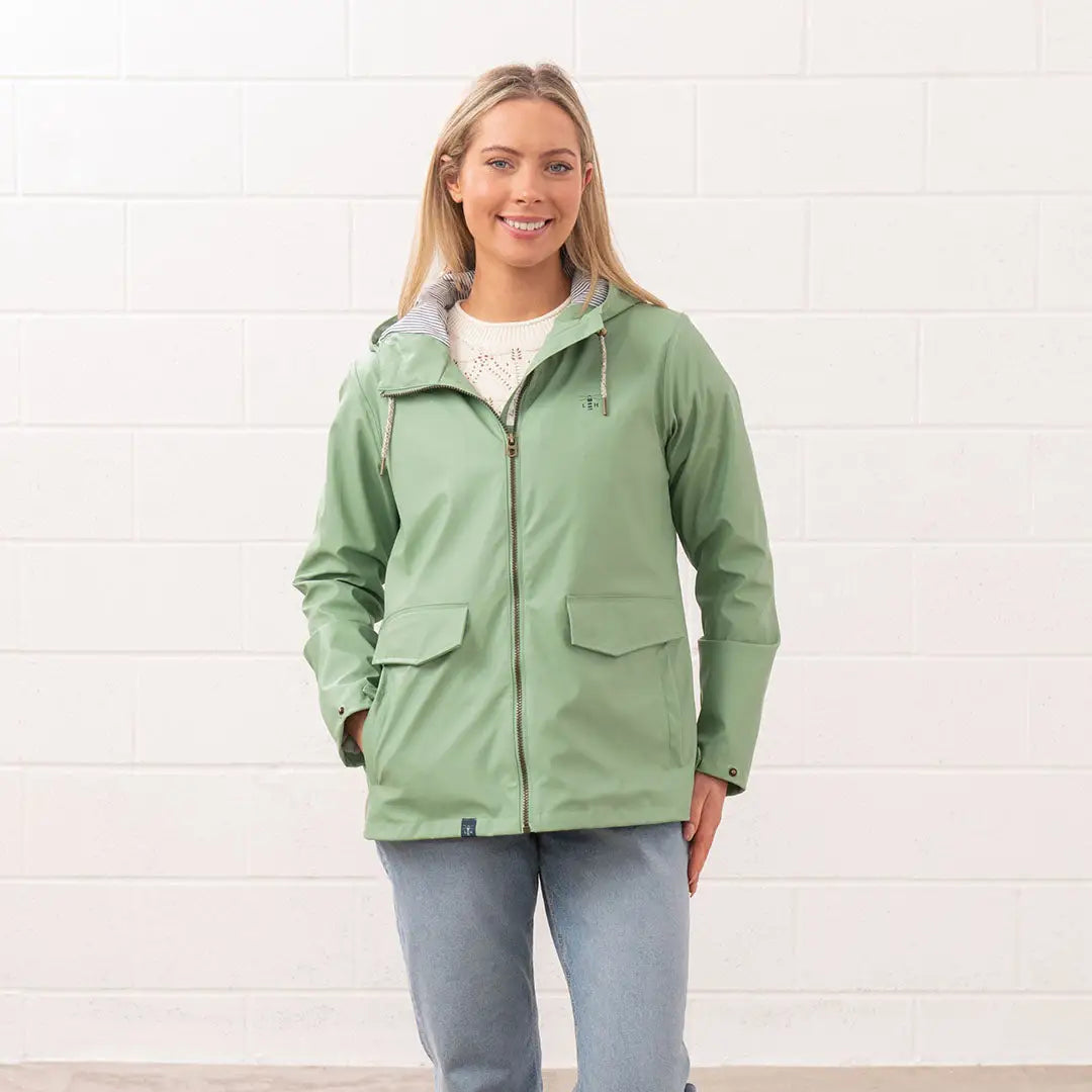 Woman in a green rain jacket, showcasing the Lighthouse Ladies Lucy Coat