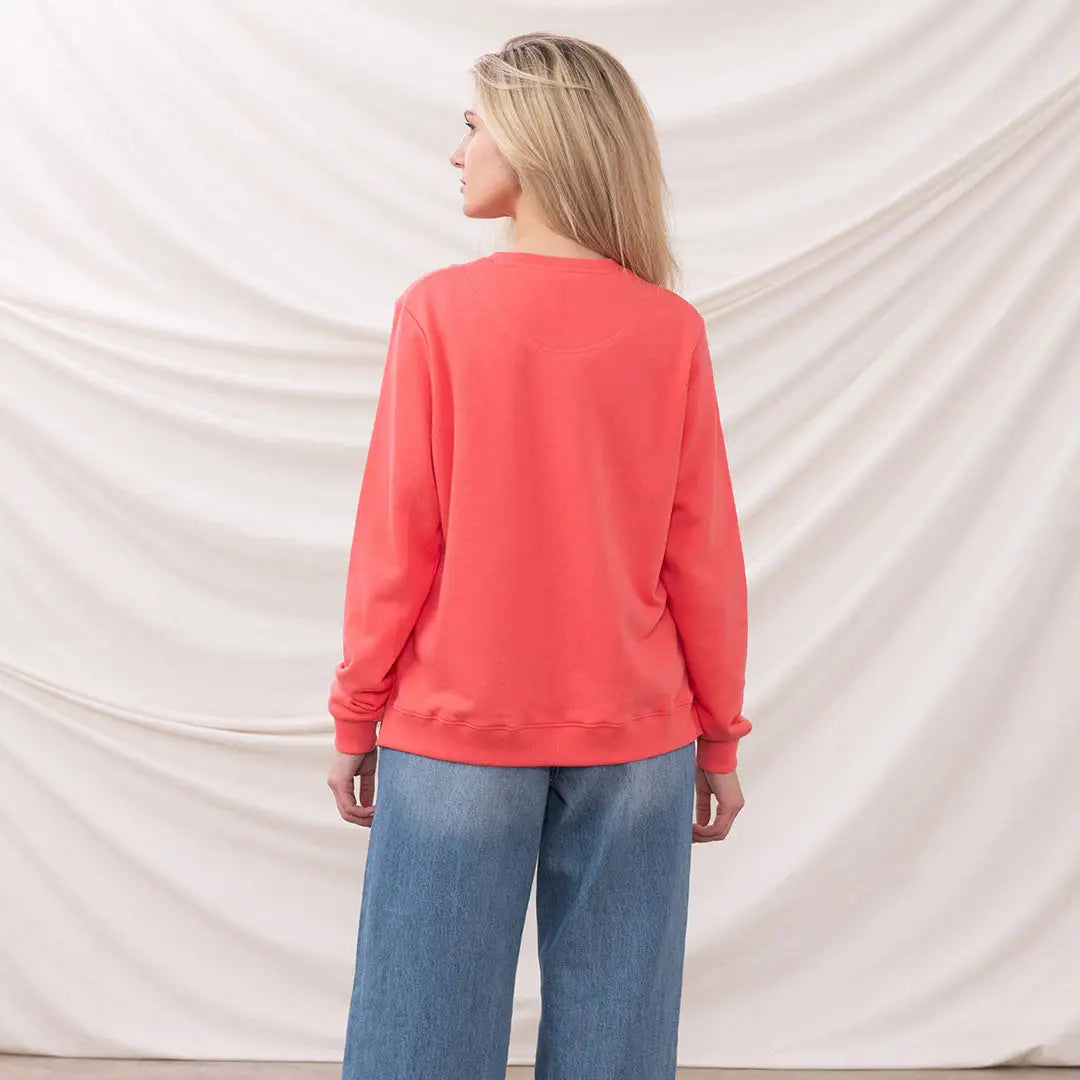 Woman in coral sweatshirt and blue jeans wearing the Lighthouse Ladies Seaside Jersey
