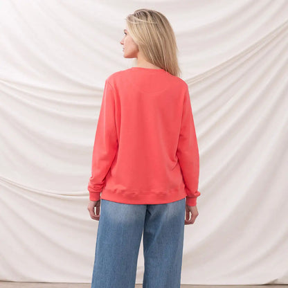 Woman in coral sweatshirt and blue jeans wearing the Lighthouse Ladies Seaside Jersey