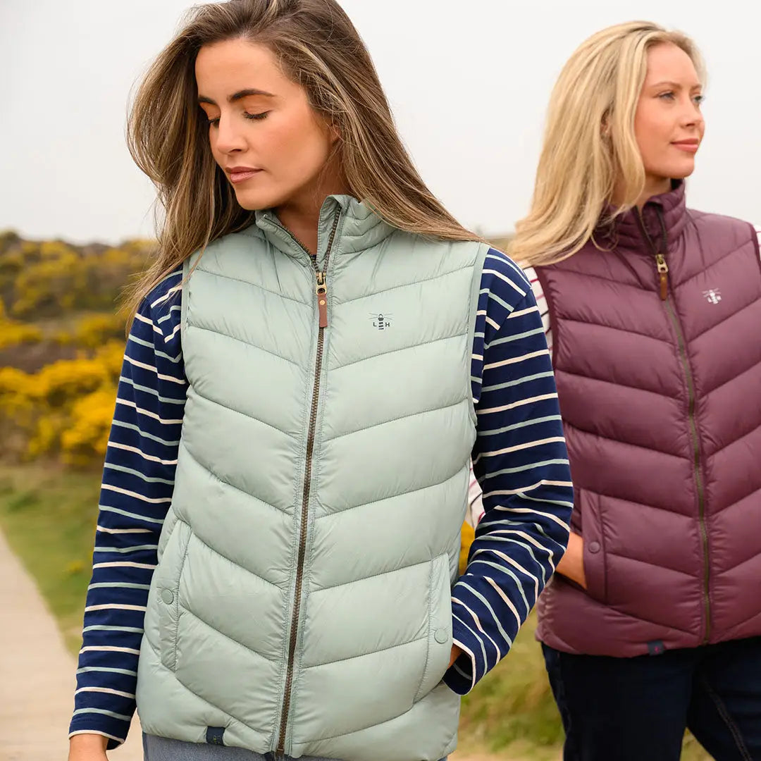 Two women modeling Lighthouse Laurel Ladies quilted puffer vests in green and burgundy