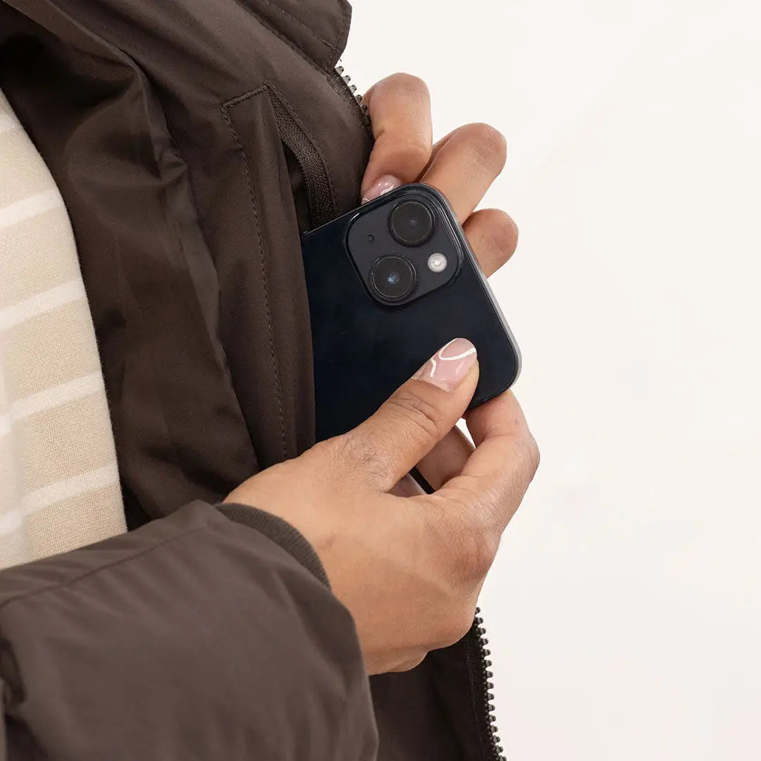 Person putting smartphone in pocket of Lighthouse Savannah Coat for stylish everyday use