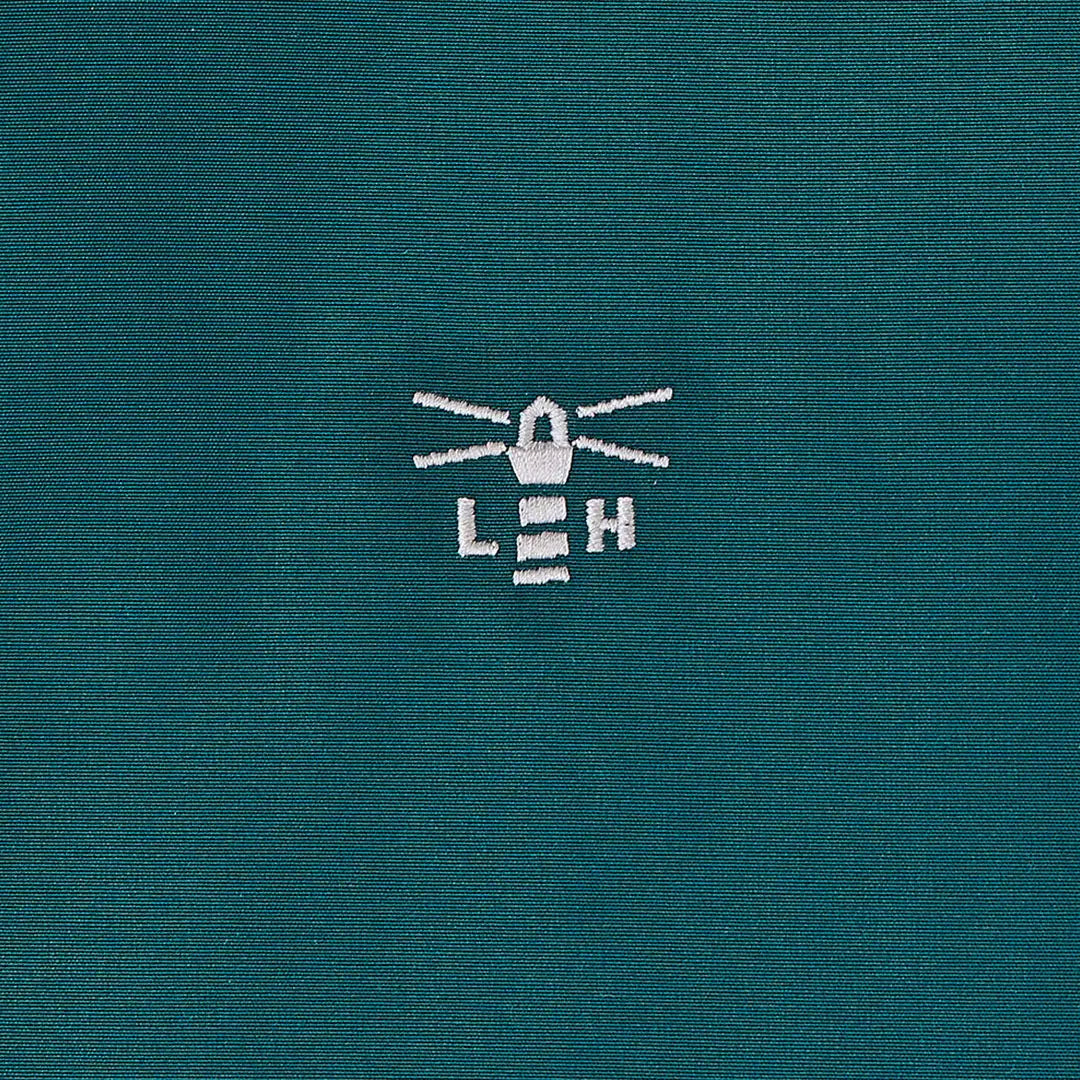 Teal country clothing coat with white embroidered lighthouse logo for outdoors and hunting