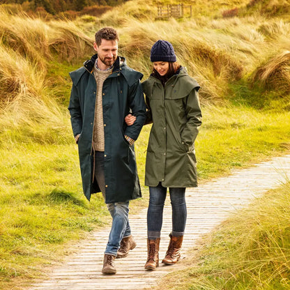 Couple in a Lighthouse Stockman waterproof rain coat strolling through tall grass