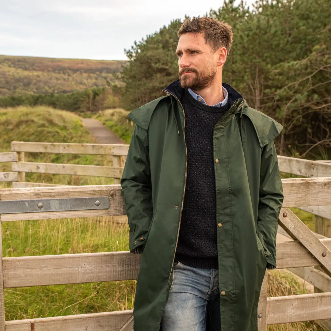 Man in a green Lighthouse Stockman Full Length Waterproof Rain Coat on wooden walkway
