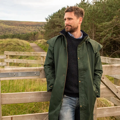 Man in a green Lighthouse Stockman Full Length Waterproof Rain Coat on wooden walkway
