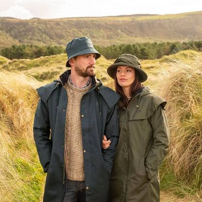 Couple in Lighthouse Stockman Full Length Waterproof Rain Coat enjoying a grassy field
