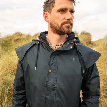 Man in a dark green Lighthouse Stockman full length waterproof rain coat with a hood