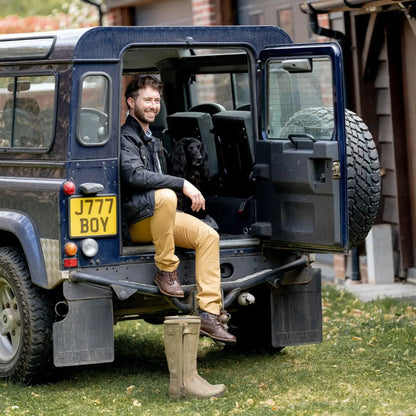 Land Rover Defender with person in doorway sporting a Mens Biker Wax Jacket