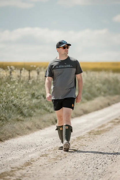 Man in boots walking on dirt road wearing New Forest 2-Tone Graphic T-Shirt in forest clothing graphic