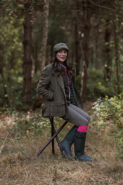 Woman in forest avon zip wellington boots with pink socks sitting on a stool