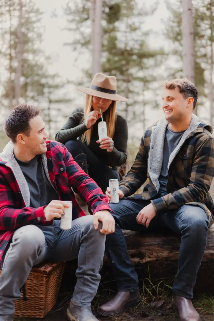 Three friends enjoying drinks in a Green Lumberjack Shirt, perfect for forest adventures