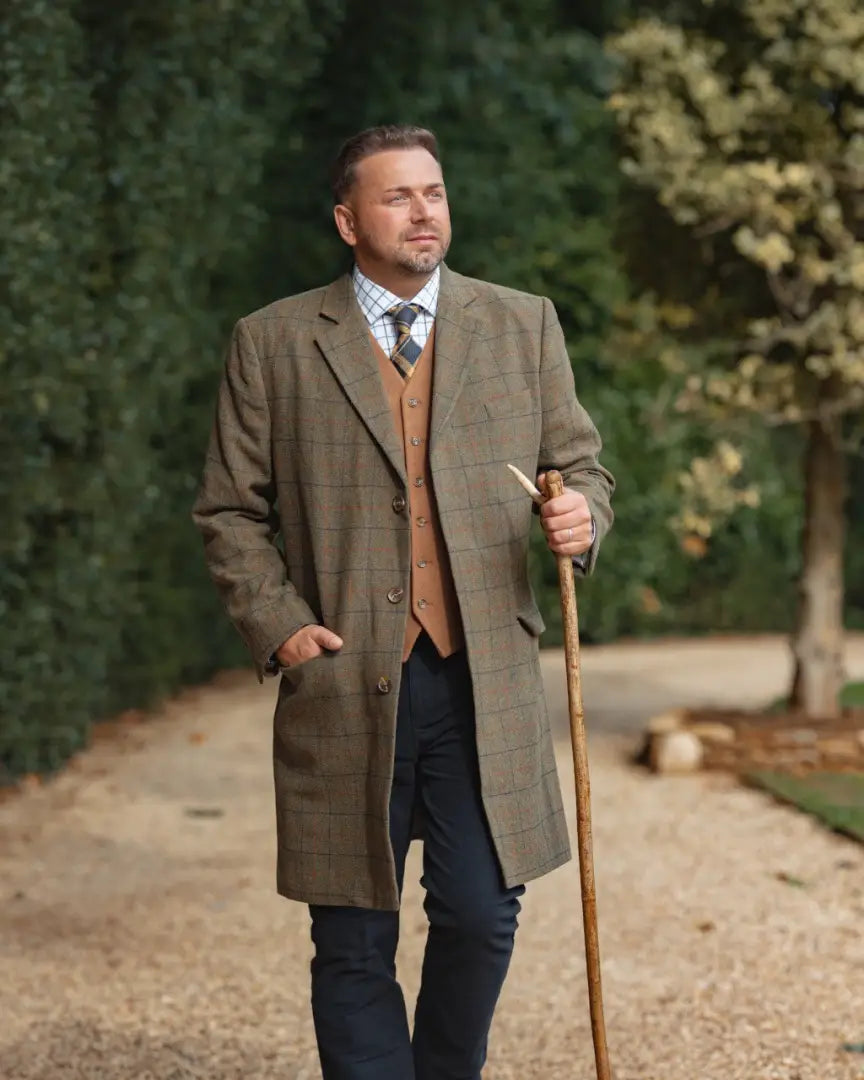 Man in a Tweed Long Coat holding a walking stick showcasing Forest Goodwood Tweed style