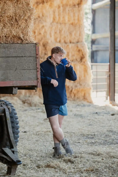 Man drinking from blue mug in New Forest Harlequin Rugby Shorts, perfect for country clothing and hunting vibes