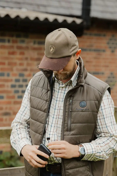 Man in brown vest and cap wearing a New Forest Heated Gilet outdoors