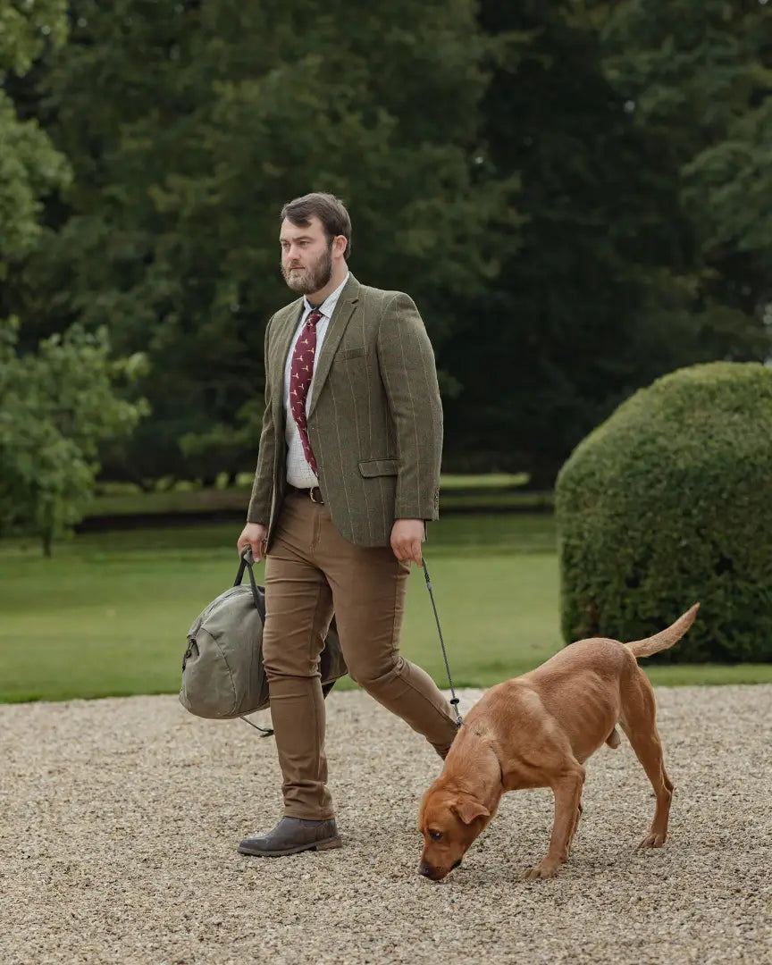 Man in Forest Heritage Tweed Blazer walking a brown dog on a leash outdoors