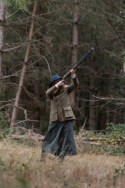 Super stylish ladies field coat in forest, person aiming rifle for hunting adventure
