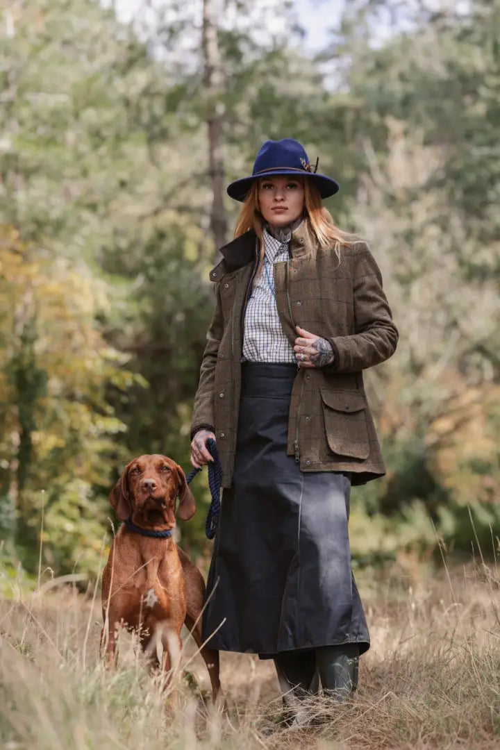 Stylish ladies field coat with woman in tweed jacket and blue hat walking a dog