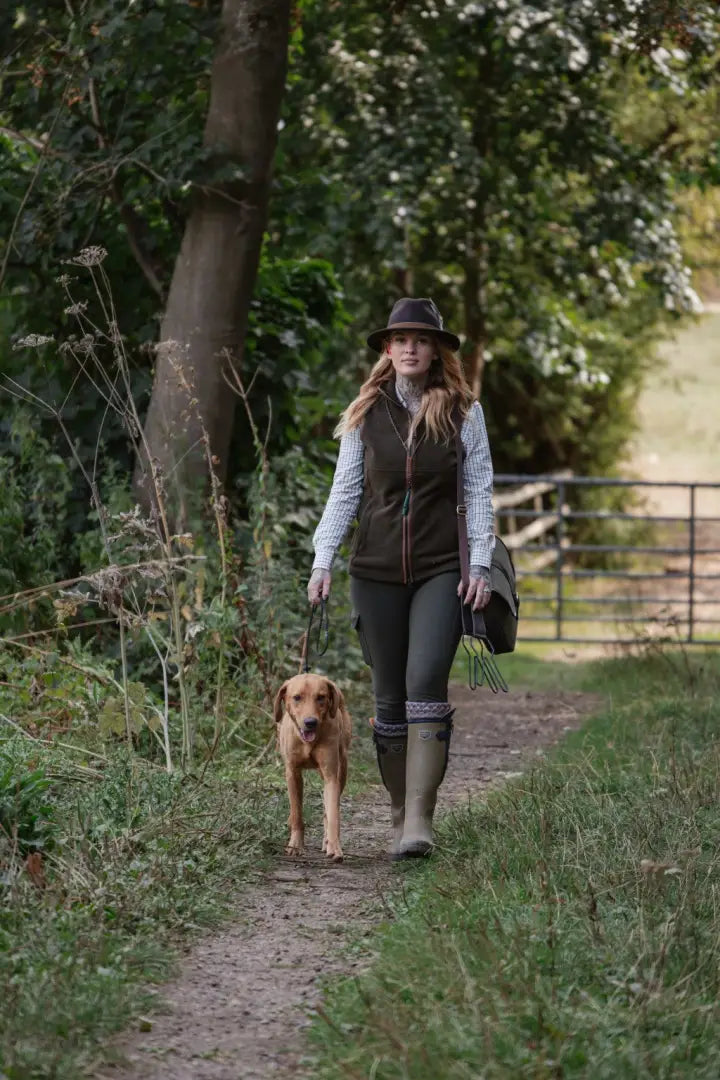Woman in a hat and vest walking her dog in country clothing outdoors with New Forest Gilet