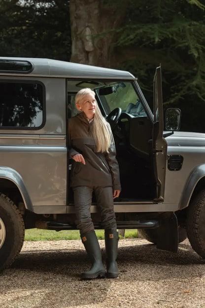 Woman in forest nightjar trousers leaning on gray SUV outdoors in nightjar trousers style