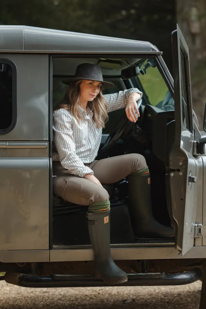 Forest ladies outdoor style with ladies outdoor stretch trousers, woman in plaid shirt in Land Rover
