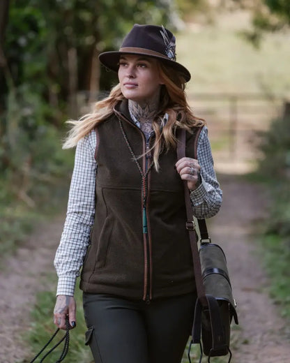 Woman in forest ladies outdoor stretch trousers with dark brown vest plaid shirt and hat