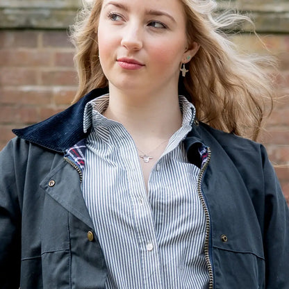 Young woman in a dark padded wax jacket over a striped shirt with long blonde hair