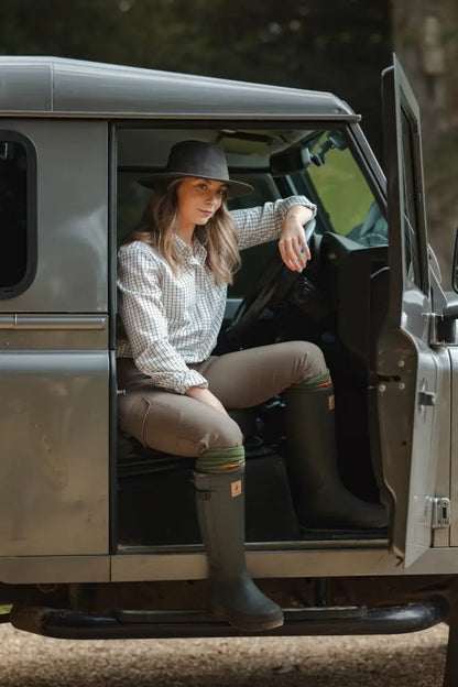 Woman in plaid shirt and wellington boots sitting in Land Rover with New Forest Tattersall Shirt