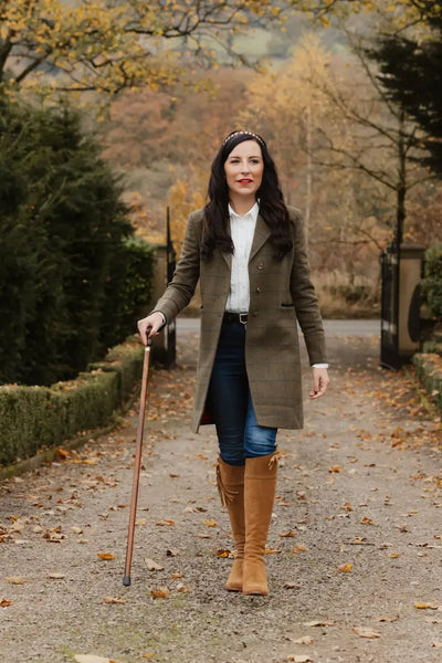 Woman in a stylish Forest Lizzie Tweed coat, confidently walking with a stick