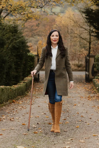 Woman in a stylish Forest Lizzie Tweed coat, confidently walking with a stick