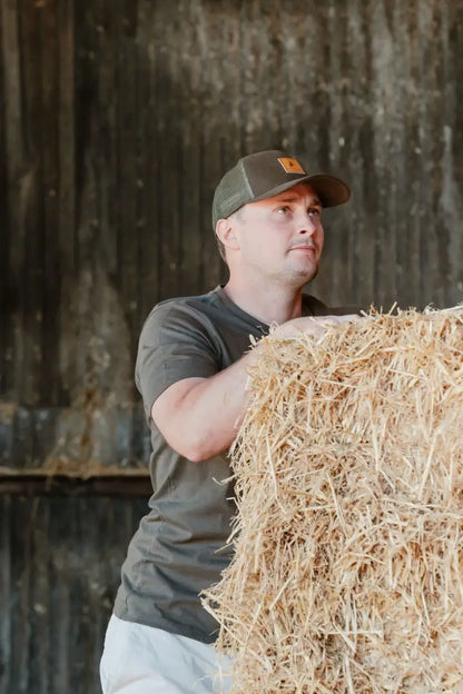 Man holding hay bale wearing New Forest Logo T-Shirt with forest clothing graphic